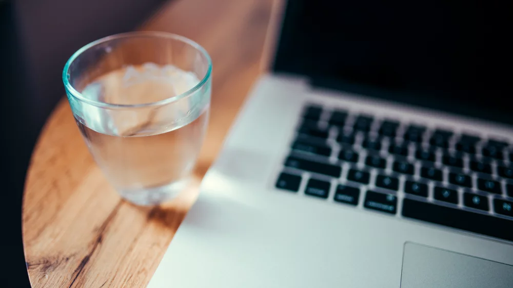 Laptop auf einem Holztisch neben einem Wasserglas